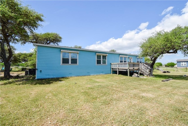 rear view of house featuring a wooden deck and a lawn