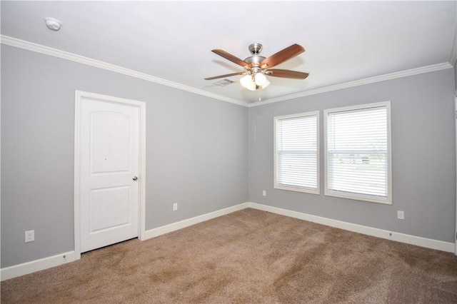 carpeted spare room with ornamental molding, ceiling fan, visible vents, and baseboards