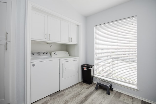 clothes washing area with cabinets, light wood-type flooring, and independent washer and dryer