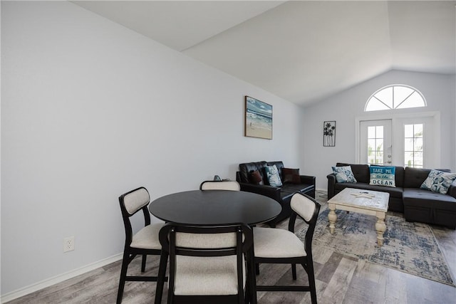 dining space featuring light wood-style flooring, lofted ceiling, and baseboards