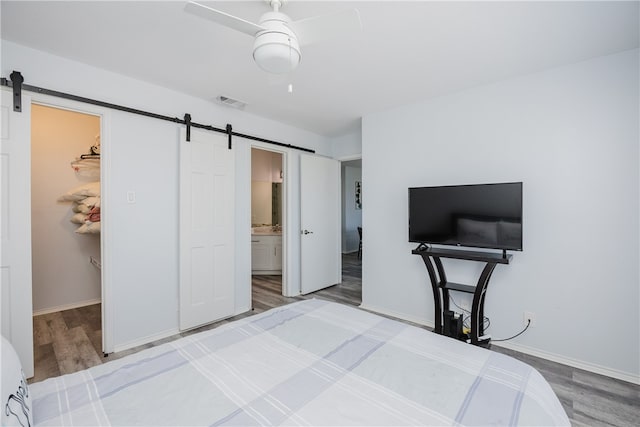 bedroom with a closet, a walk in closet, a barn door, and wood-type flooring