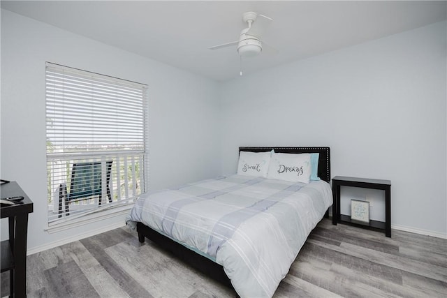 bedroom featuring wood finished floors, baseboards, and a ceiling fan