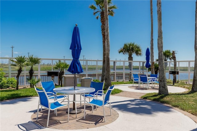 view of patio / terrace featuring outdoor dining area, a water view, and fence