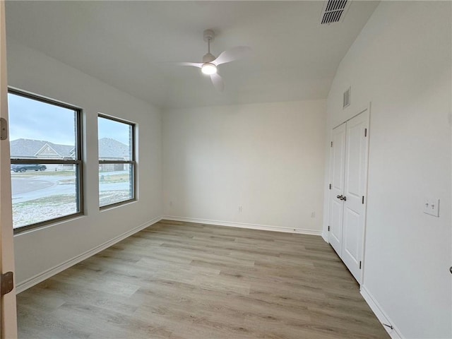 empty room featuring light wood finished floors, a ceiling fan, visible vents, and baseboards