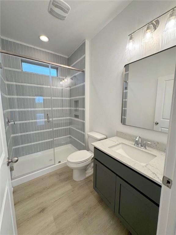 bathroom featuring visible vents, toilet, a stall shower, vanity, and wood finished floors