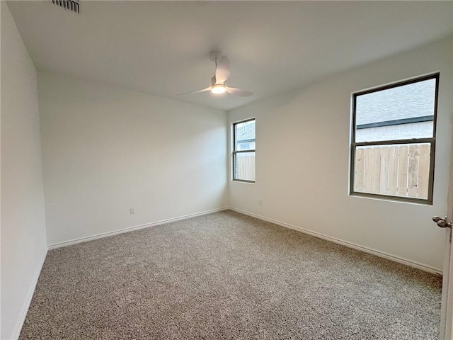 carpeted empty room with baseboards, visible vents, and a ceiling fan