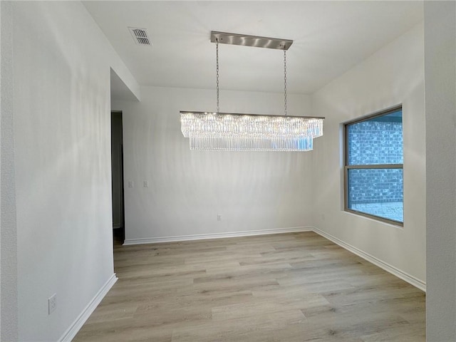 unfurnished dining area with baseboards, light wood-type flooring, visible vents, and a notable chandelier