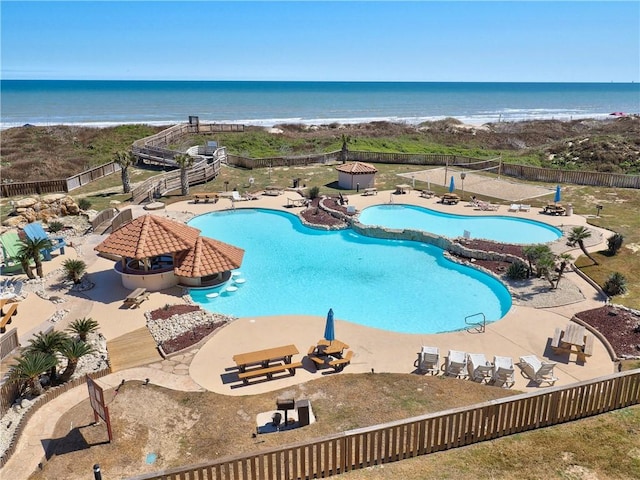 community pool with a patio area, a fenced backyard, and a water view