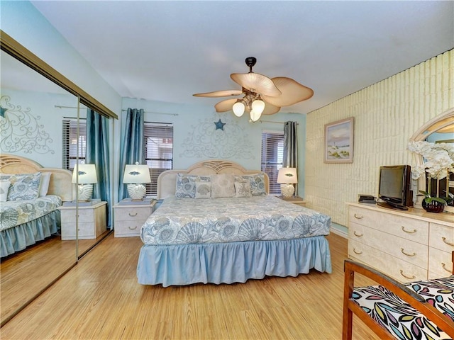 bedroom with ceiling fan, a closet, wood finished floors, and wallpapered walls