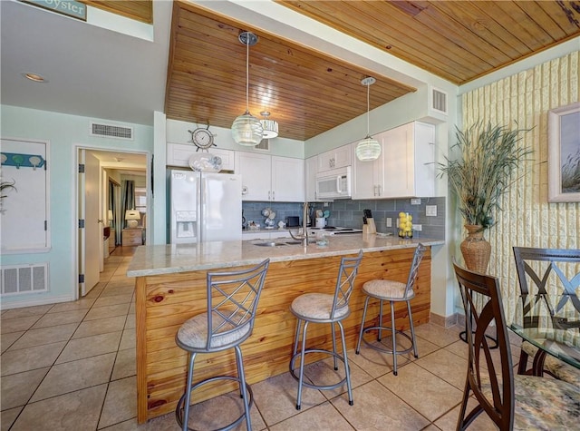 kitchen with white appliances, a peninsula, visible vents, and wooden ceiling