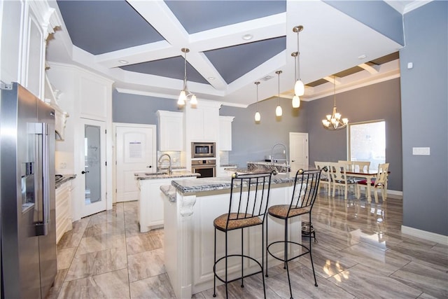 kitchen with stone countertops, stainless steel appliances, white cabinetry, and an island with sink