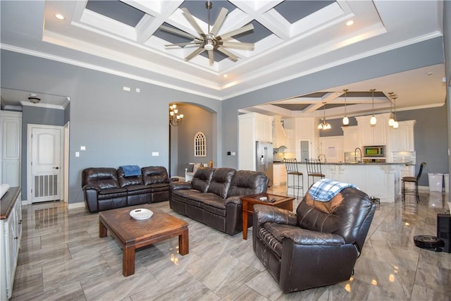 living room featuring beam ceiling, ceiling fan with notable chandelier, coffered ceiling, and ornamental molding