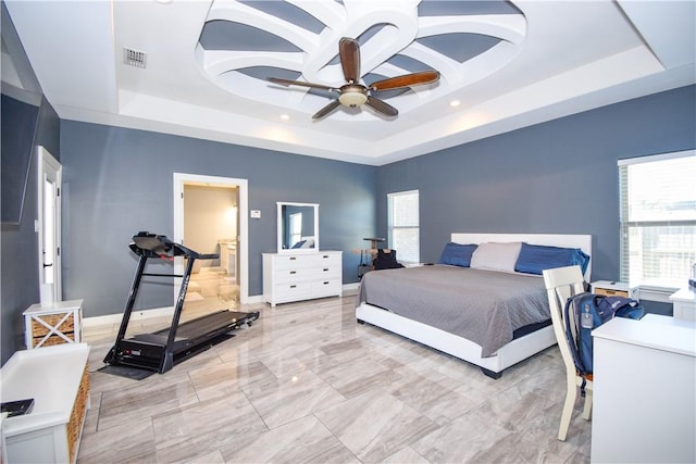 bedroom with multiple windows, a tray ceiling, and ceiling fan