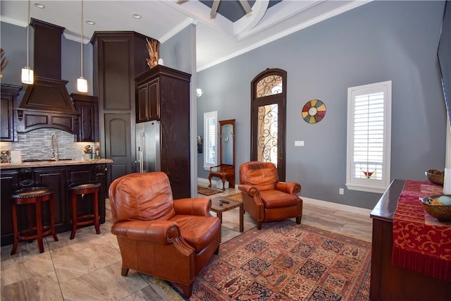 living room featuring a towering ceiling, sink, and ornamental molding