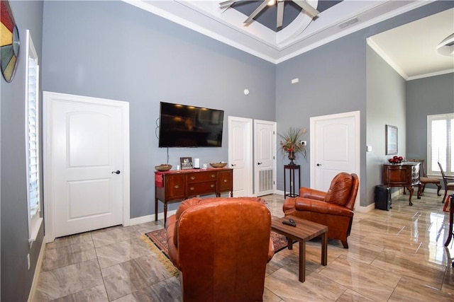 living room with ceiling fan, crown molding, and a towering ceiling