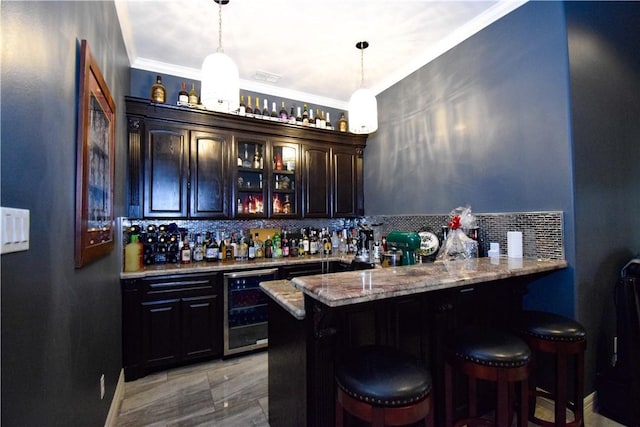 bar with wine cooler, decorative backsplash, light stone countertops, decorative light fixtures, and dark brown cabinets