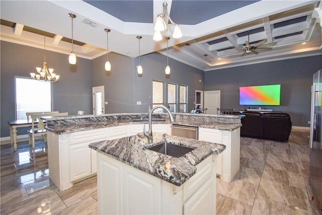 kitchen with sink, hanging light fixtures, a large island with sink, a towering ceiling, and ceiling fan with notable chandelier