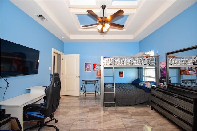 bedroom with ceiling fan and a tray ceiling