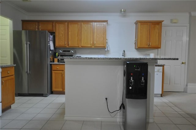 kitchen featuring light tile patterned floors, light stone counters, freestanding refrigerator, brown cabinetry, and crown molding