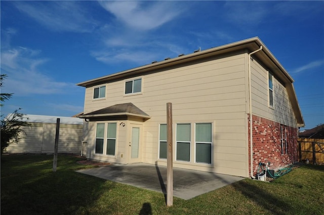 rear view of property with brick siding, a yard, fence, and a patio