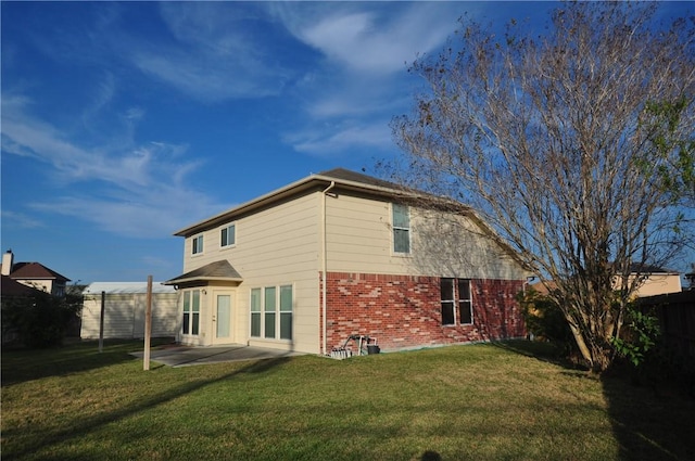 rear view of house featuring a patio area, brick siding, a yard, and a fenced backyard