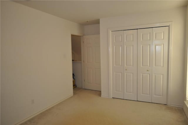 unfurnished bedroom with baseboards, a closet, and light colored carpet