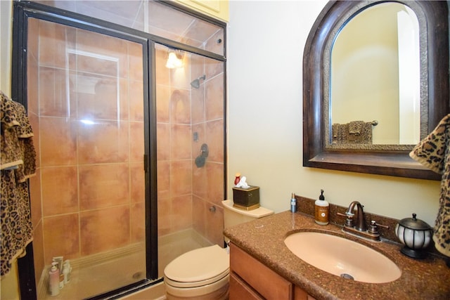 bathroom featuring vanity, toilet, and a shower with shower door