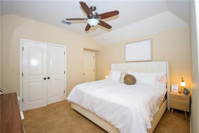 bedroom with ceiling fan, a closet, light carpet, and vaulted ceiling