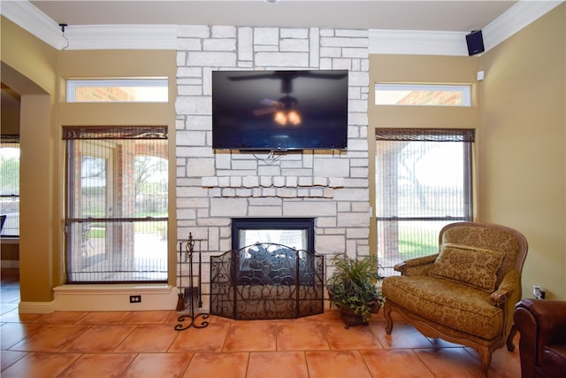 living area featuring tile patterned floors, crown molding, a fireplace, and a healthy amount of sunlight