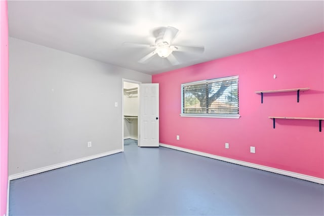 unfurnished bedroom with a closet, a walk in closet, concrete floors, and ceiling fan