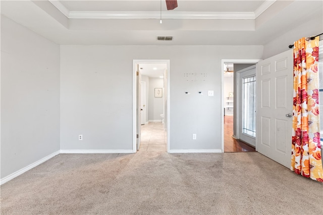 unfurnished bedroom with ceiling fan, a raised ceiling, crown molding, and carpet