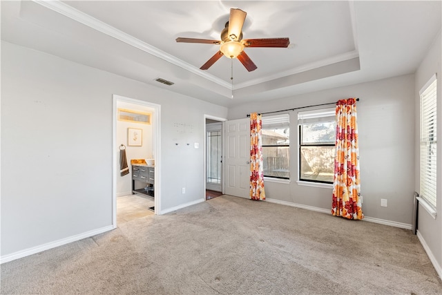 unfurnished bedroom featuring ensuite bathroom, light colored carpet, ceiling fan, and a raised ceiling