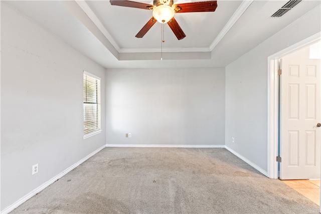 spare room with ceiling fan, light colored carpet, crown molding, and a raised ceiling