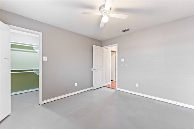 unfurnished bedroom featuring a closet, a spacious closet, concrete floors, and ceiling fan