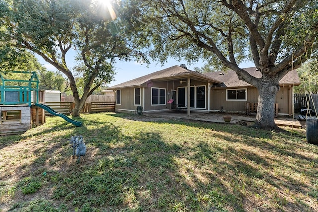 rear view of house featuring a playground, a patio, and a yard