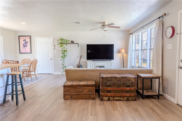 living room with hardwood / wood-style floors, ceiling fan, and a textured ceiling