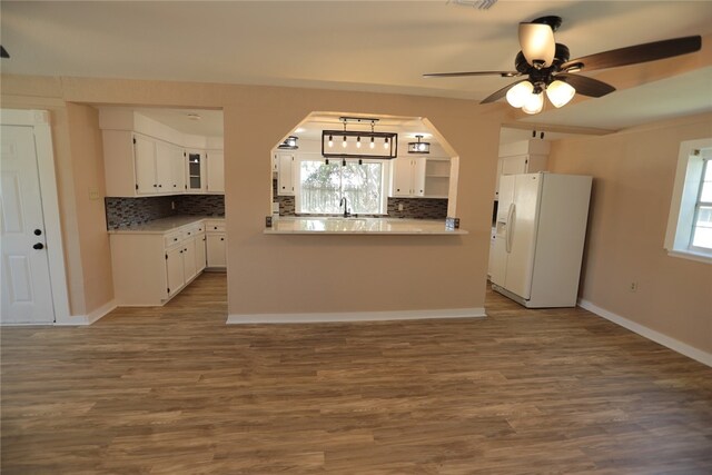 kitchen with backsplash, dark hardwood / wood-style flooring, white fridge with ice dispenser, white cabinets, and kitchen peninsula