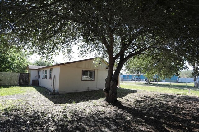 view of side of property featuring central AC unit and a lawn