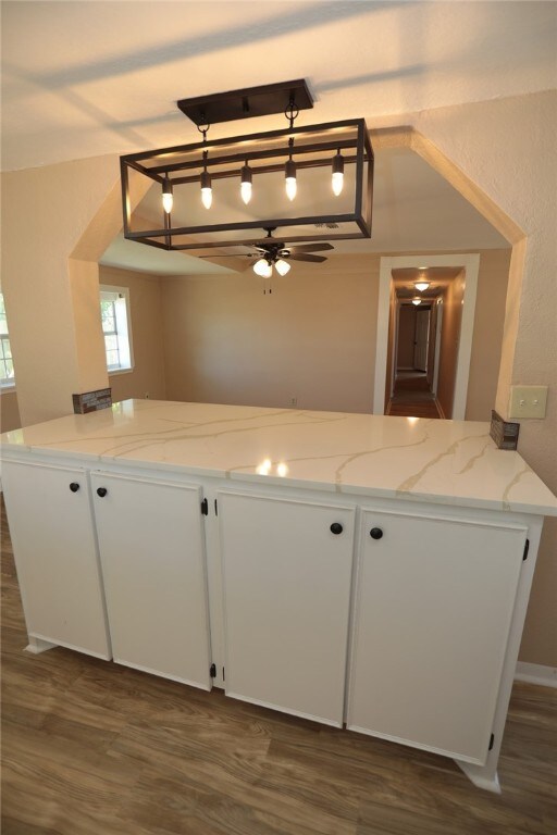 kitchen featuring white cabinetry, dark hardwood / wood-style floors, ceiling fan, and light stone countertops