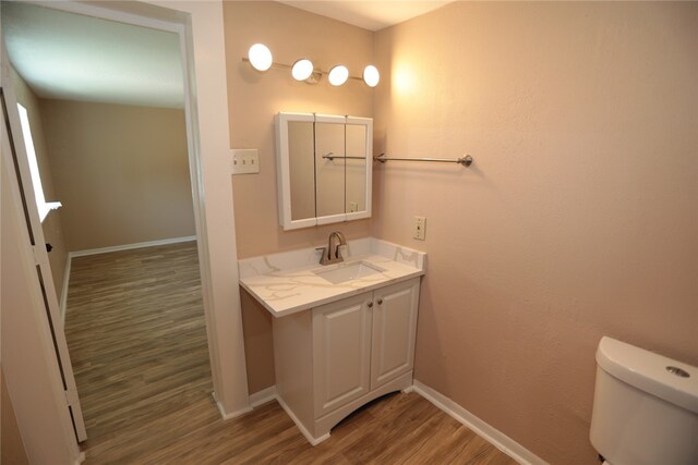 bathroom with hardwood / wood-style flooring, vanity, and toilet