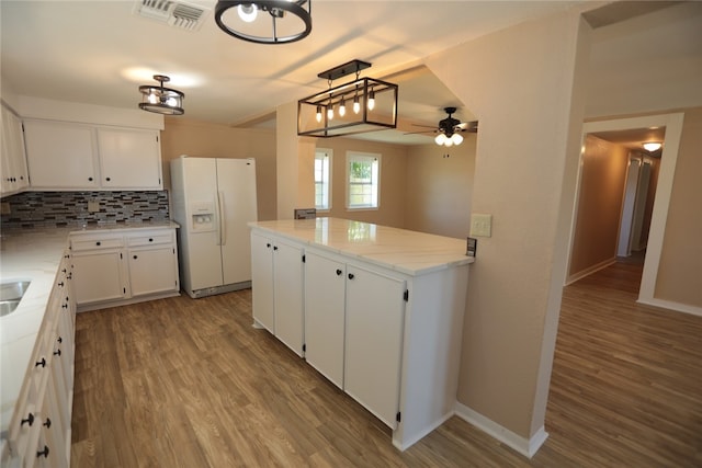 kitchen with white cabinetry, backsplash, white fridge with ice dispenser, pendant lighting, and light hardwood / wood-style flooring