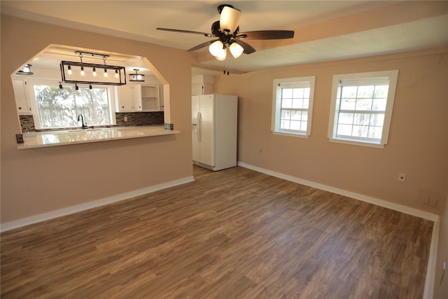 kitchen featuring hardwood / wood-style flooring, ceiling fan, white fridge with ice dispenser, backsplash, and white cabinets