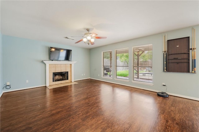 unfurnished living room with a ceiling fan, baseboards, a tiled fireplace, and wood finished floors