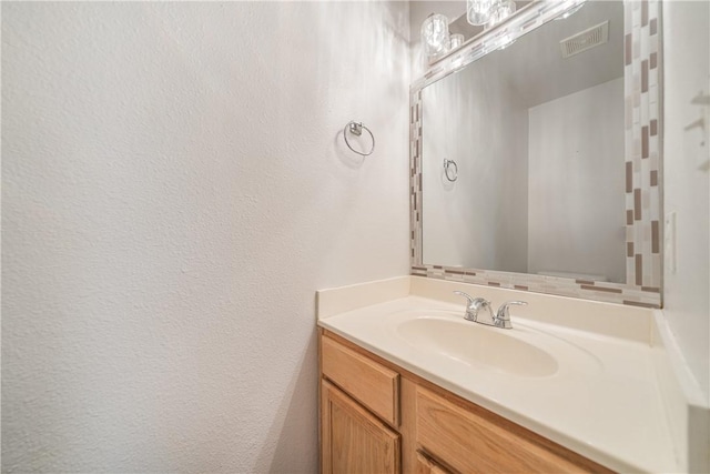 bathroom with vanity, a textured wall, and visible vents