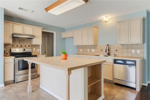 kitchen featuring visible vents, stainless steel appliances, a sink, light countertops, and under cabinet range hood