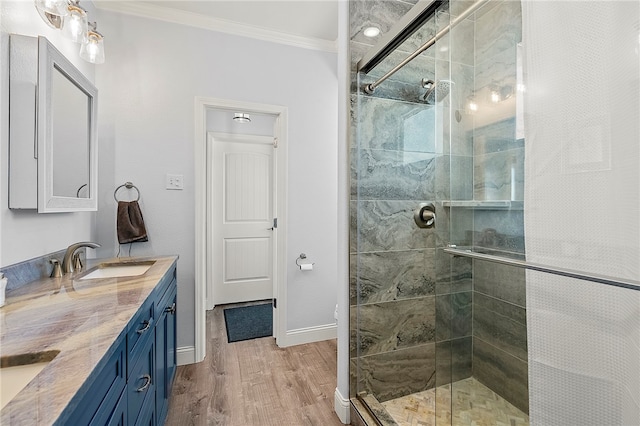 bathroom with vanity, hardwood / wood-style flooring, ornamental molding, and a shower with shower door