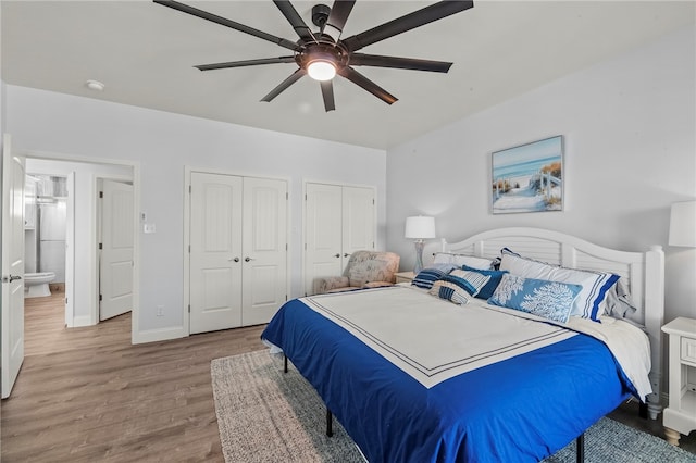 bedroom with wood-type flooring, two closets, and ceiling fan