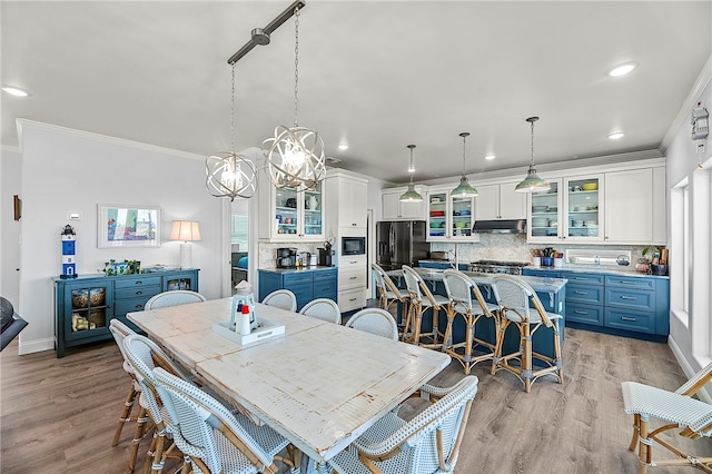 dining room with ornamental molding, a wealth of natural light, a chandelier, and light hardwood / wood-style floors