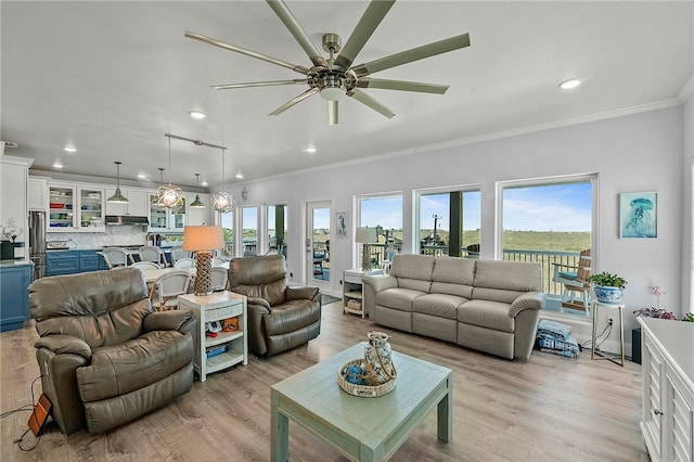 living room featuring light wood-type flooring, a wealth of natural light, and crown molding