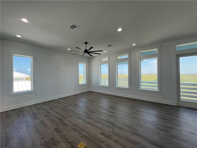 unfurnished room featuring visible vents, brick wall, baseboards, recessed lighting, and dark wood-style floors